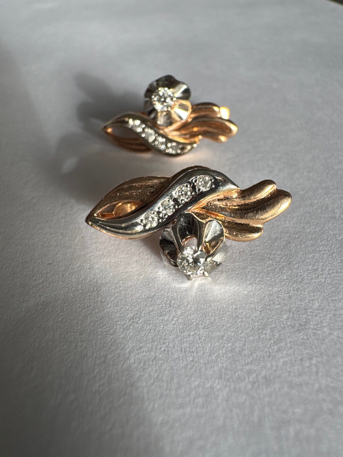 עגילי זהב 14 קראט בעיצוב מתעגל ואלגנטי המשובצים יהלומים נוצצים .