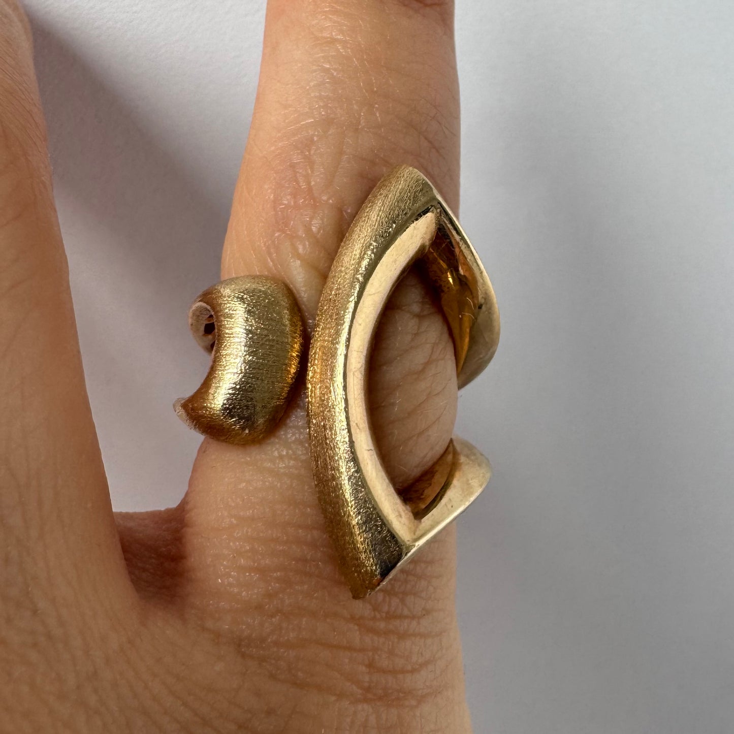 14K gold sculptural ring with a bold, modern design featuring flowing, asymmetrical lines.