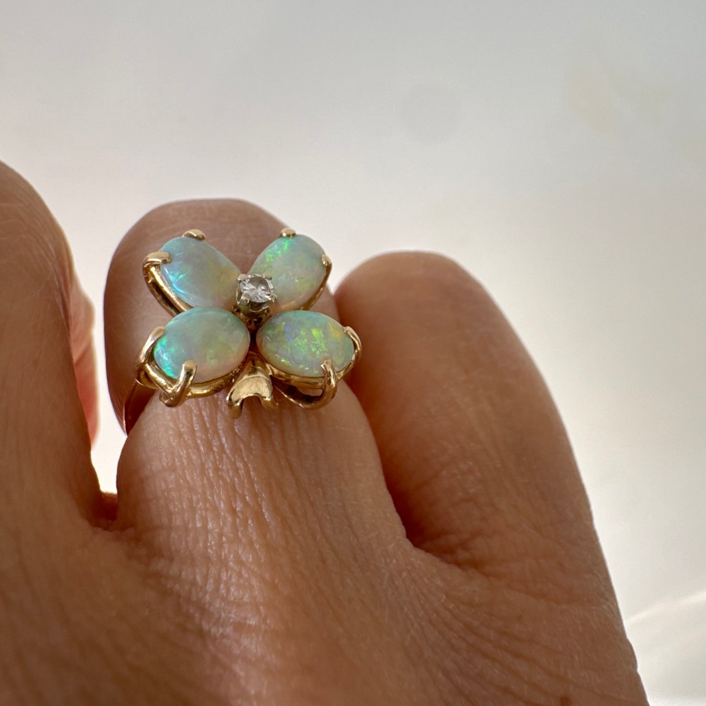 טבעת זהב 14 קראט בעיצוב פרח, משובצת ארבע אבני אופל בחיתוך טיפה ובמרכז יהלום טבעי.