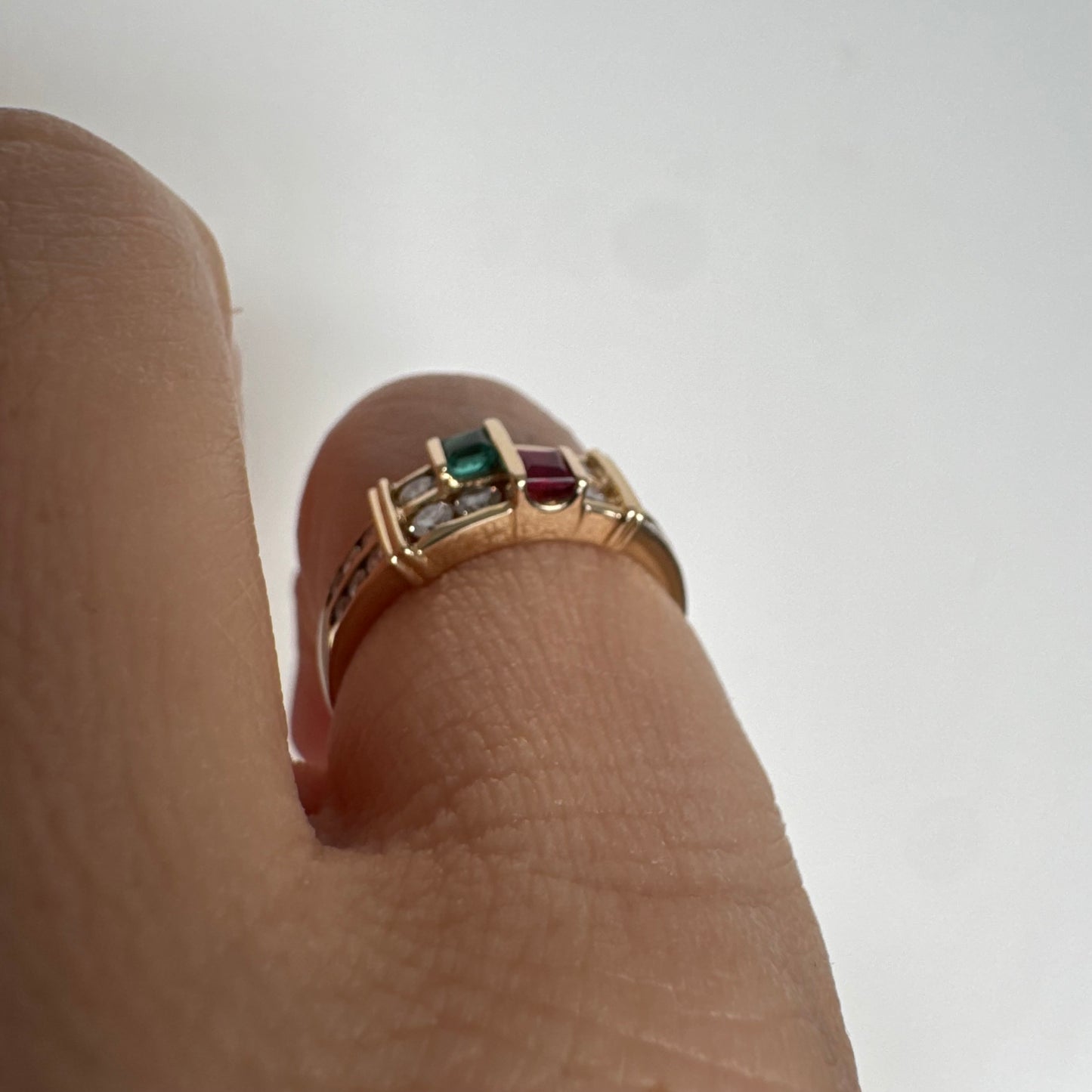 טבעת זהב צהוב 18 קראט בעיצוב גאומטרי מדורג, משובצת יהלומים עגולים לצד אבני אמרלד ורובי בחיתוך מלבני.