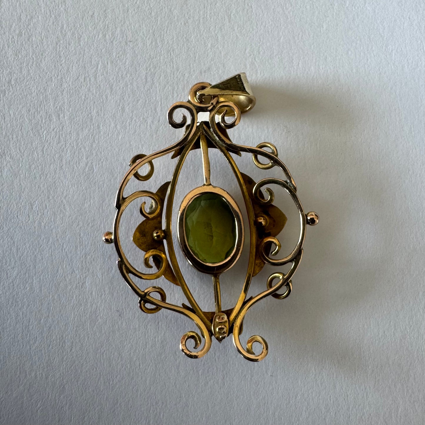 9K gold pendant featuring an oval-cut Peridot in a vibrant green hue.