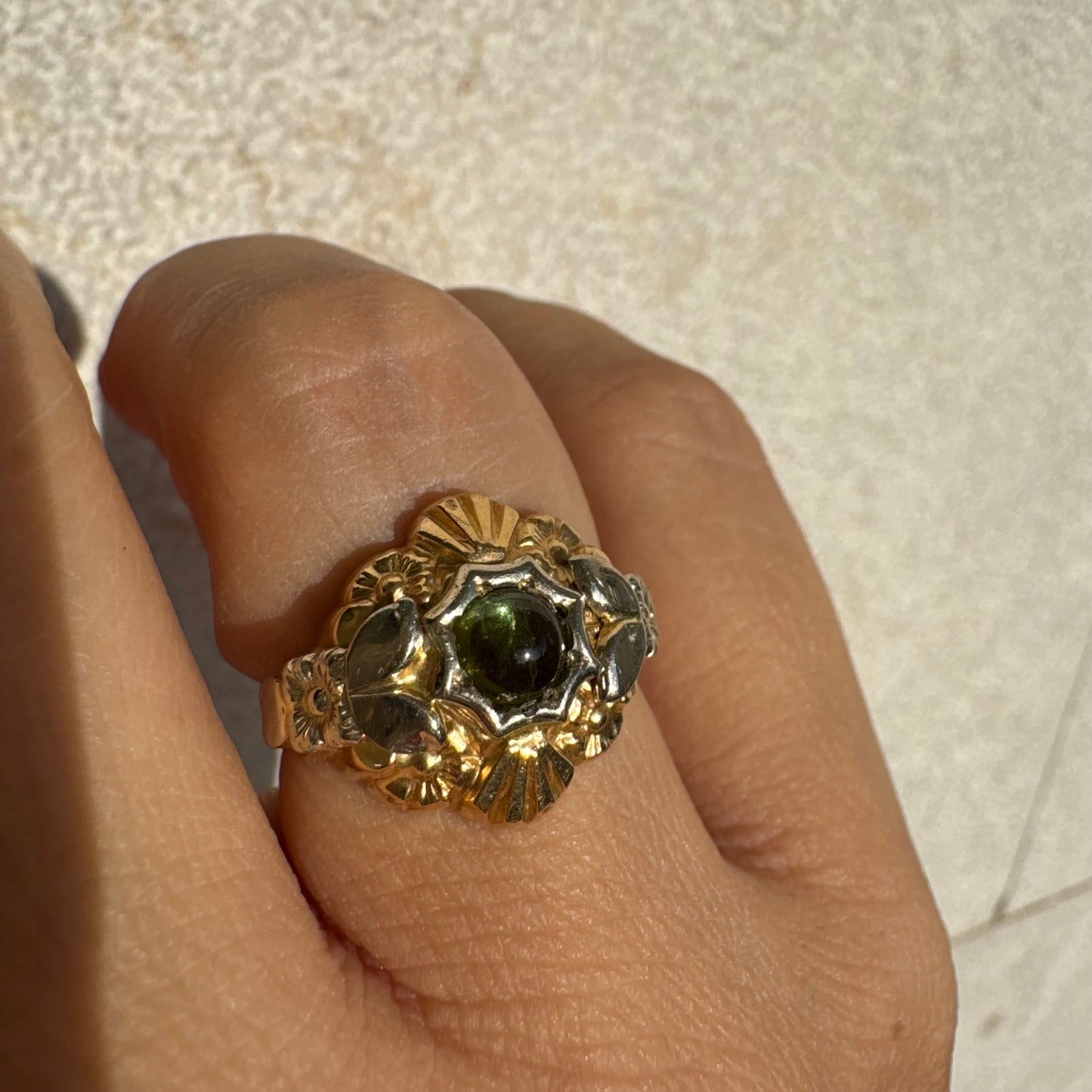 טבעת זהב בשני גוונים 18 קראט בעיצוב ייחודי, משובצת אבן טורמלין ירוק בגוון עמוק ועשיר.