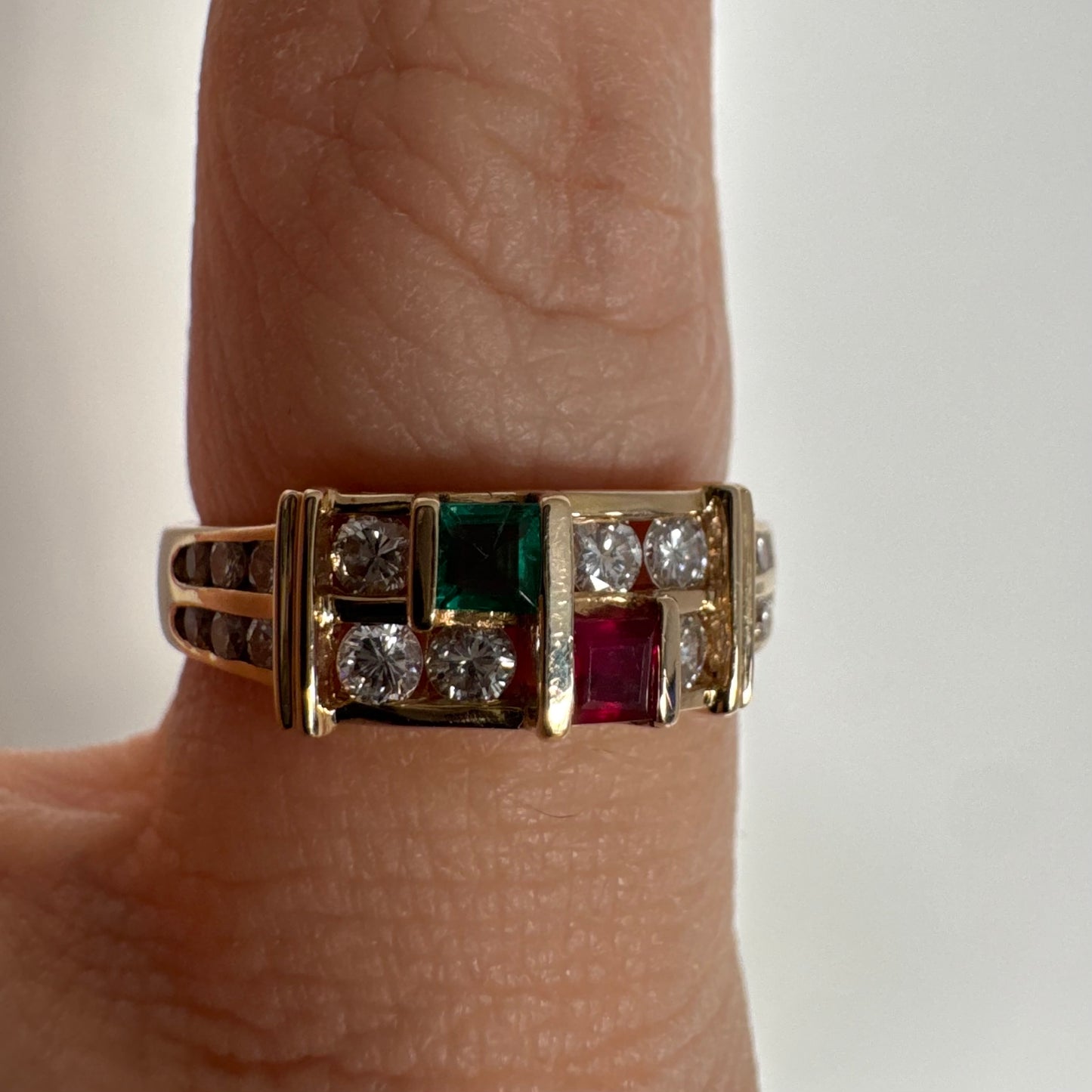 טבעת זהב צהוב 18 קראט בעיצוב גאומטרי מדורג, משובצת יהלומים עגולים לצד אבני אמרלד ורובי בחיתוך מלבני.