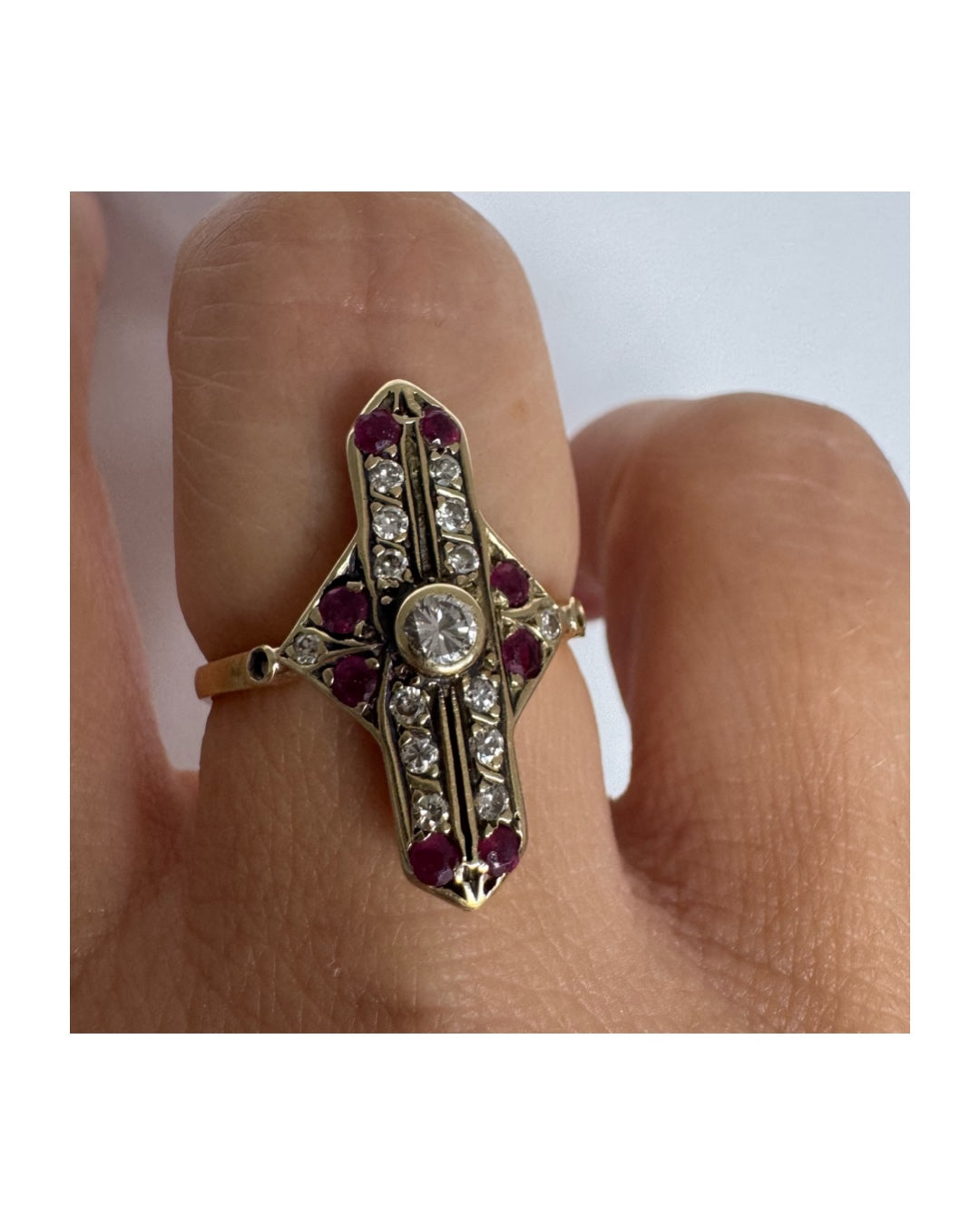 18K gold ring featuring a striking geometric design, set with a central Diamond surrounded by sparkling Diamonds and rich red Rubies.
