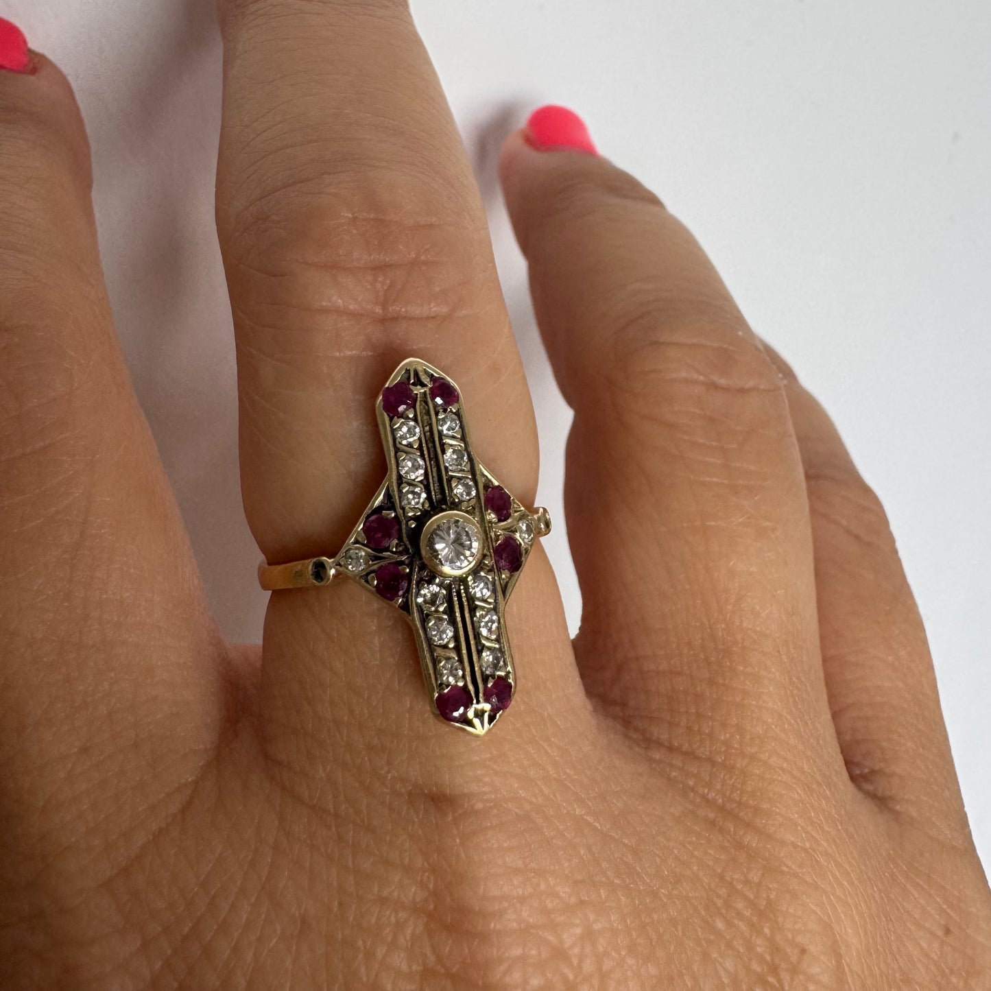 18K gold ring featuring a striking geometric design, set with a central Diamond surrounded by sparkling Diamonds and rich red Rubies.