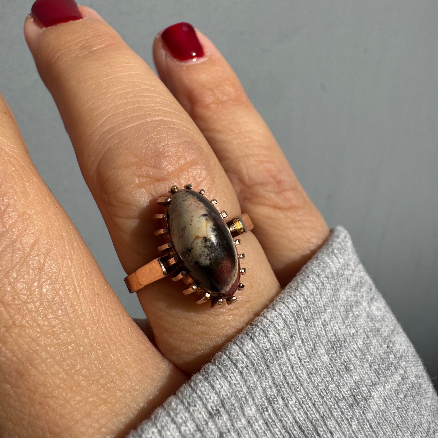 טבעת זהב 14 קראט משובצת אבן ג’ספר ייחודית בגווני קרם, שחור ואדום. 