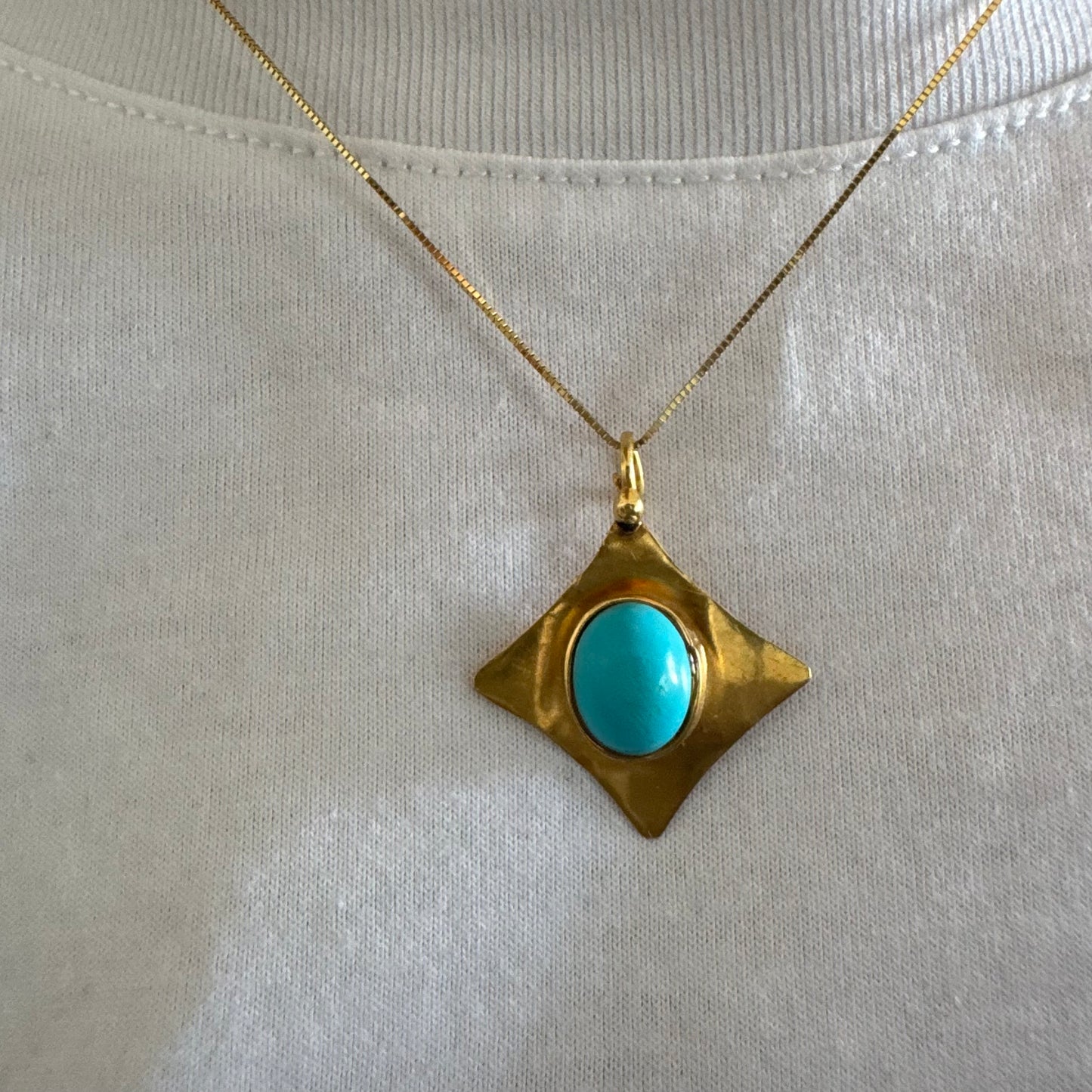 18K gold pendant set with a vibrant Turquoise stone in a bold, geometric design.