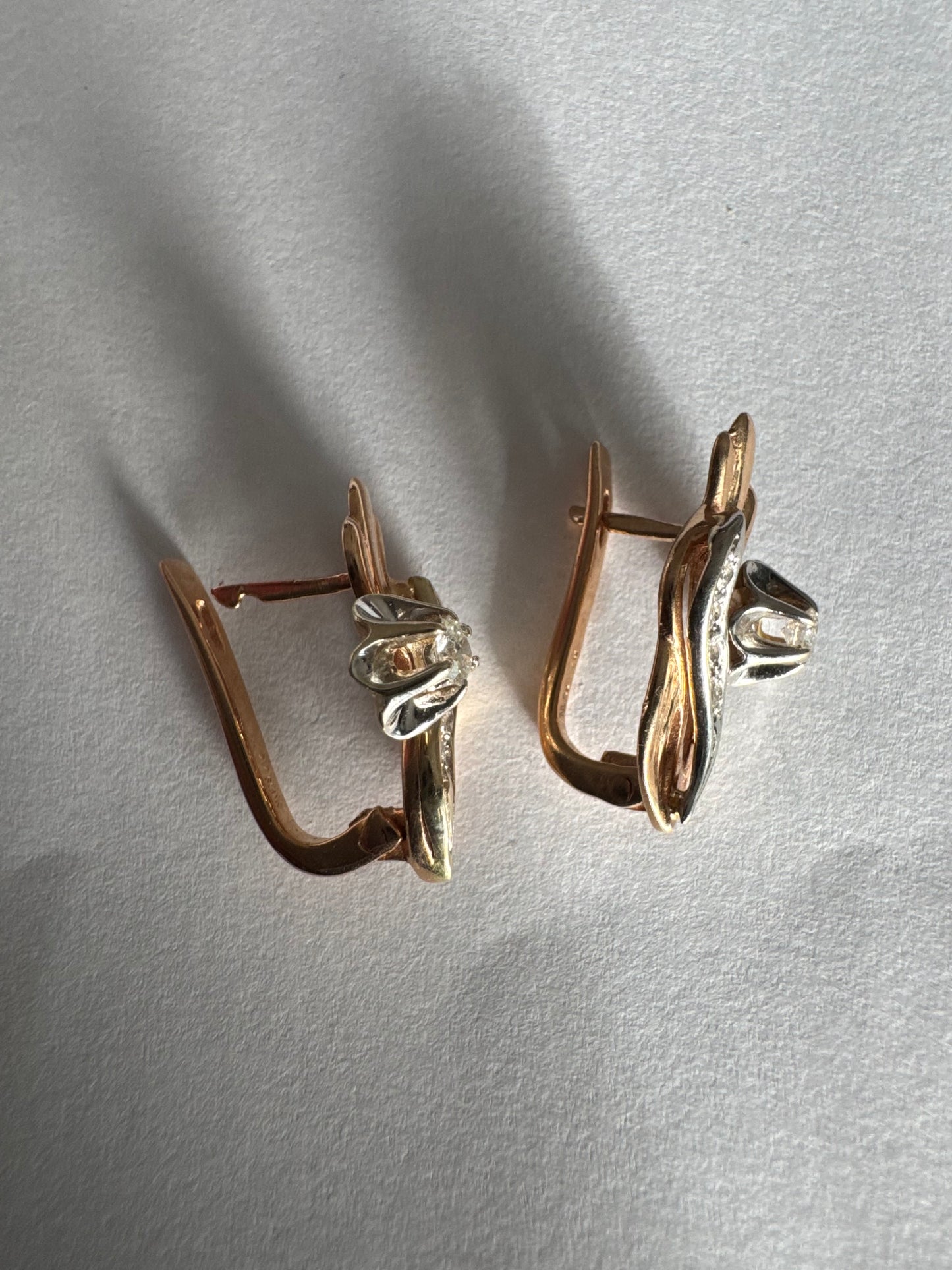 עגילי זהב 14 קראט בעיצוב מתעגל ואלגנטי המשובצים יהלומים נוצצים .