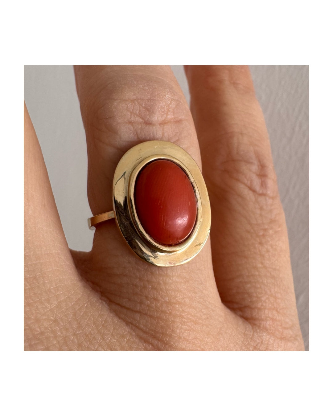 טבעת זהב 18 קראט משובצת אבן קורל אובלית בגימור קבושון, משובצת במסגרת חלקה ונקייה.