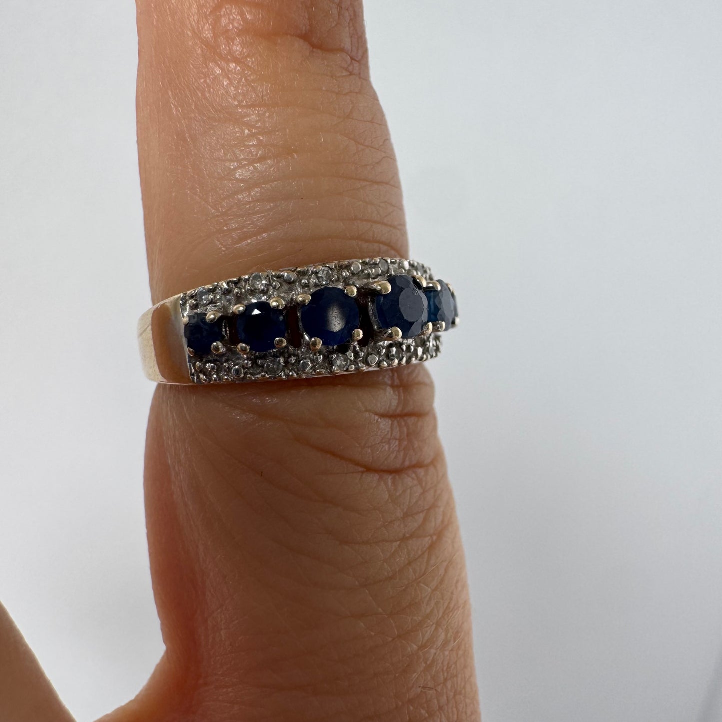 18K gold ring set with deep blue sapphires in a classic round cut, framed by two shimmering rows of brilliant Diamonds.
