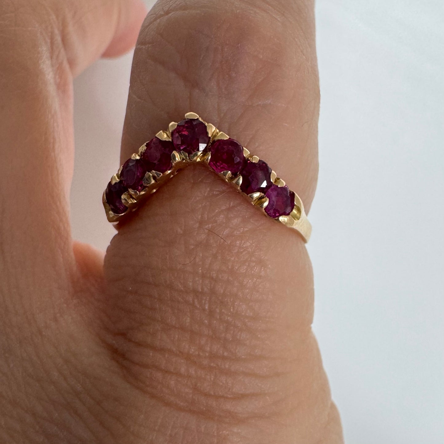 18K gold ring set with vivid red rubies in a distinctive V-shaped design.