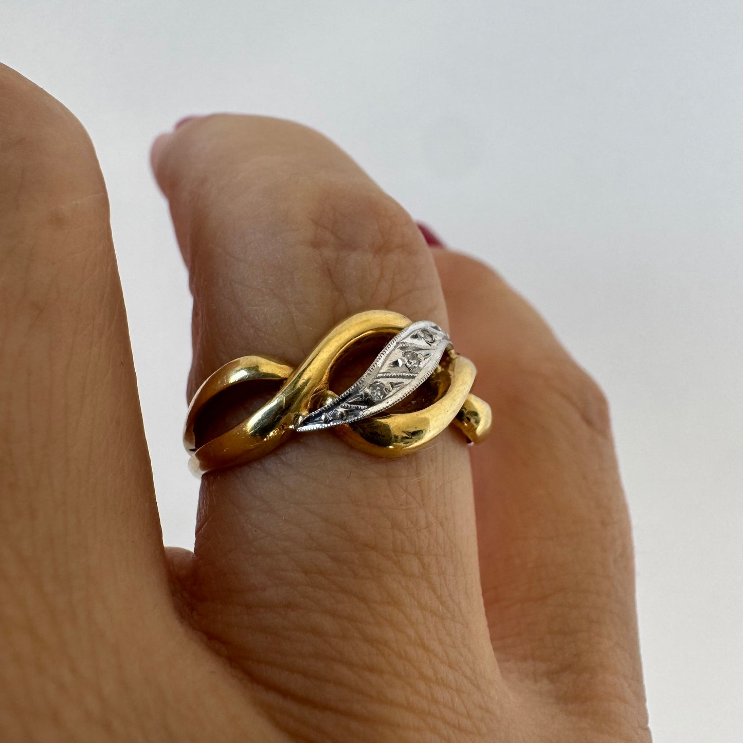 18K gold knot-style ring featuring a white gold center accented with delicate Diamonds.