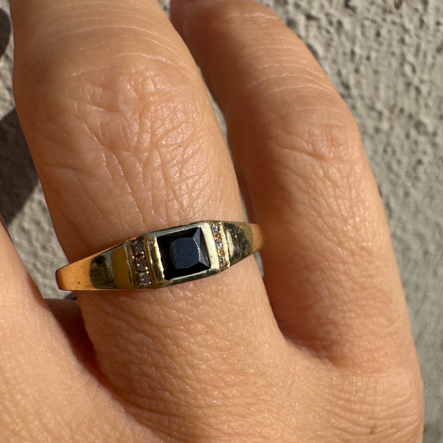 טבעת זהב 14 קראט משובצת אבן ספינל שחור בחיתוך ריבועי במרכז ויהלומים קטנים משני הצדדים.