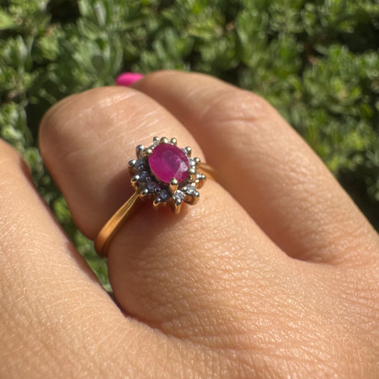 18K gold ring set with an oval Ruby at the center, surrounded by a halo of Diamonds
