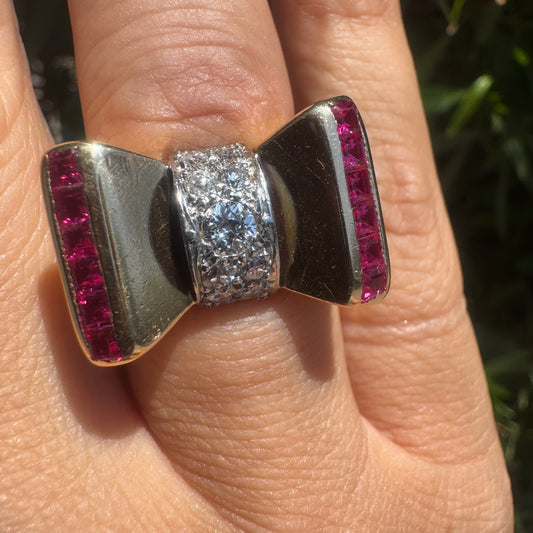 18K gold bow-shaped ring set with pavé Diamonds at the center and rows of square-cut Rubies on the sides.