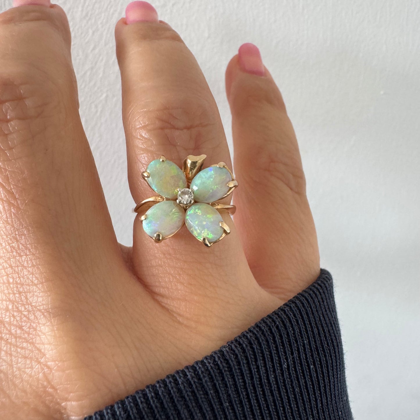 טבעת זהב 14 קראט בעיצוב פרח, משובצת ארבע אבני אופל בחיתוך טיפה ובמרכז יהלום טבעי.