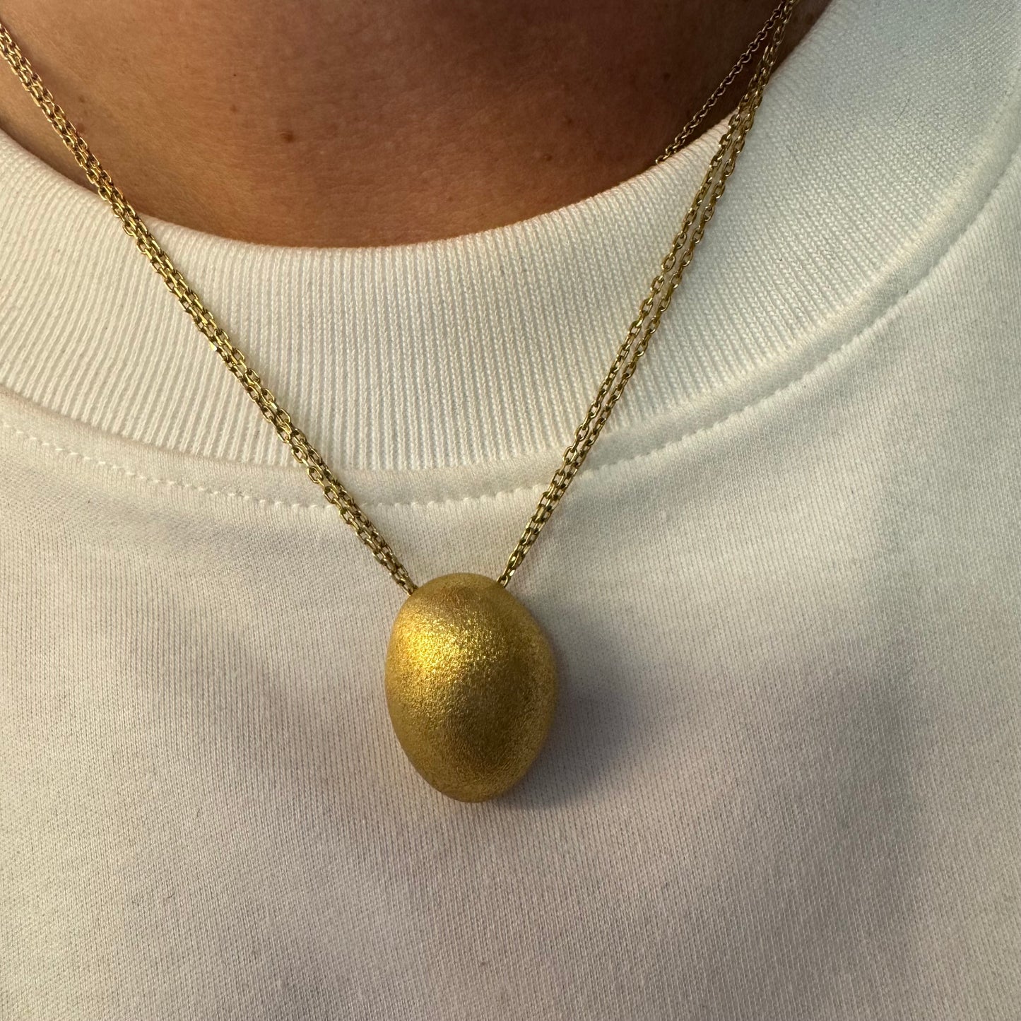 An elegant H.Stern 18K gold necklace featuring a bold oval pendant with a softly textured matte finish. 
(Golden Stones collection)