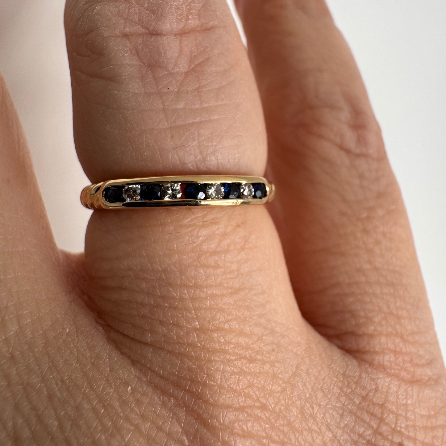 18K gold ring featuring a refined channel setting of deep blue Sapphires accented with Diamonds.