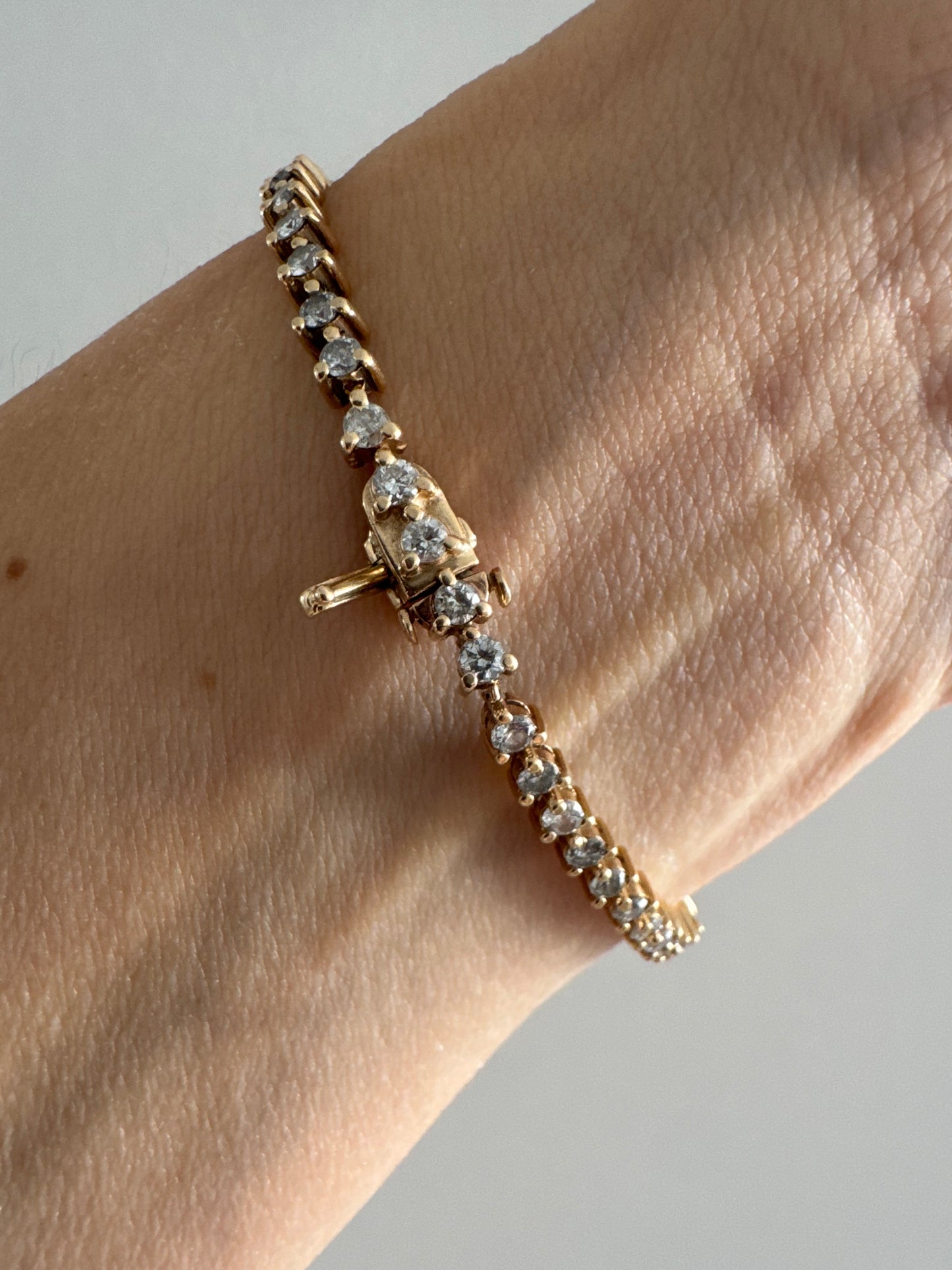 14K gold tennis bracelet set with a continuous line of round Diamonds, creating a delicate and elegant sparkle.