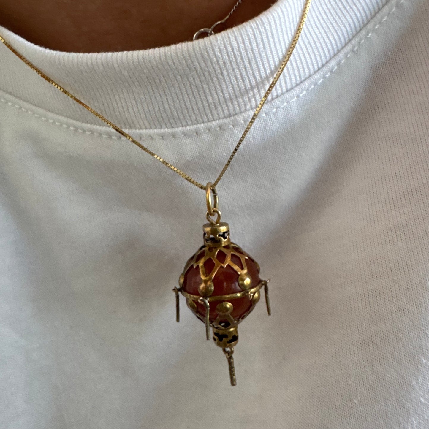9K gold pendant set with a deep red stone in an intricate openwork design.