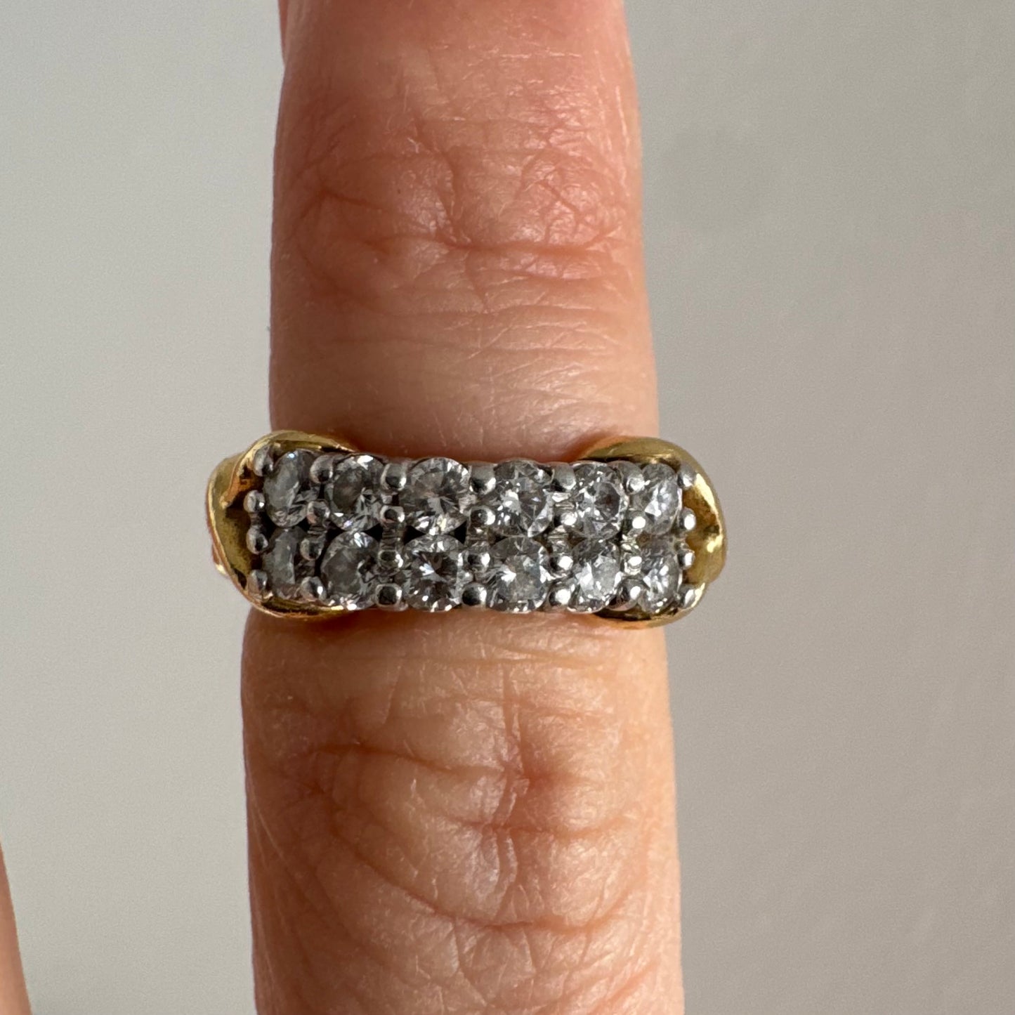 טבעת זהב צהוב 18 קראט משובצת יהלומים עגולים בשתי שורות צפופות, במבנה מלבני מעוגל.