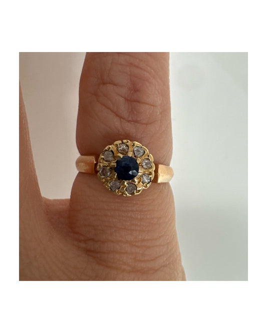 טבעת זהב 14 קראט משובצת ספיר מרכזי מוקף הילה של יהלומים בחיתוך עגול.