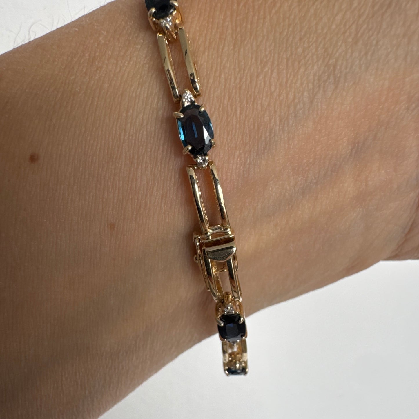 צמיד זהב צהוב 14 קראט משובץ אבני טופז כחולות בחיתוך אובלי, עם יהלומים המשובצים ביניהן להוספת ברק עדין.