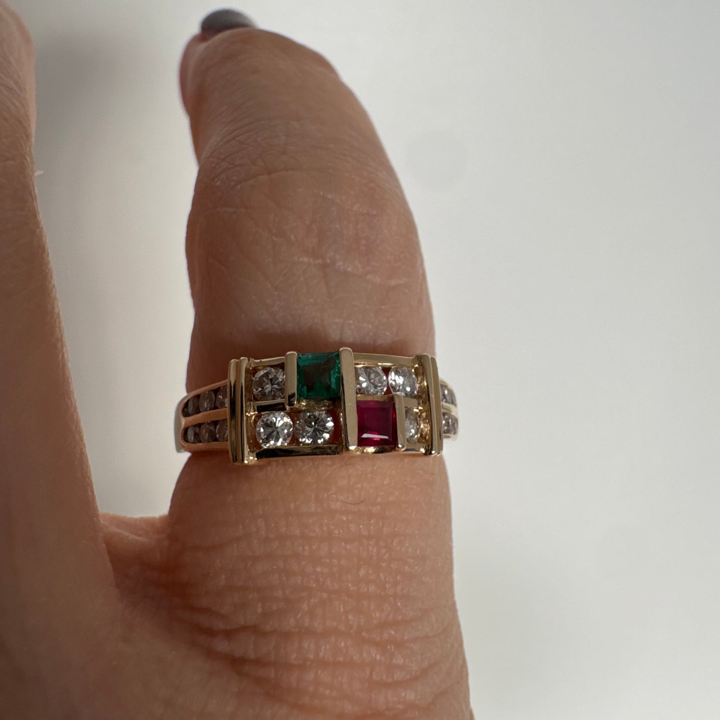 טבעת זהב צהוב 18 קראט בעיצוב גאומטרי מדורג, משובצת יהלומים עגולים לצד אבני אמרלד ורובי בחיתוך מלבני.