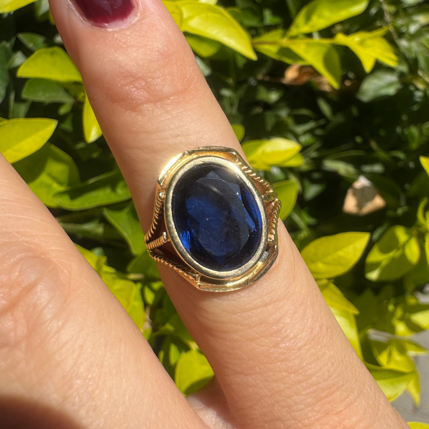 18K yellow gold ring set with a large oval deep blue Sapphire set in an ornate bezel.
