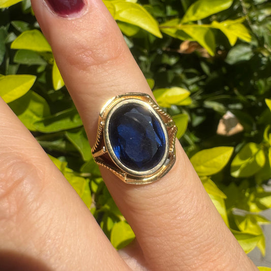 18K yellow gold ring set with a large oval deep blue Sapphire set in an ornate bezel.