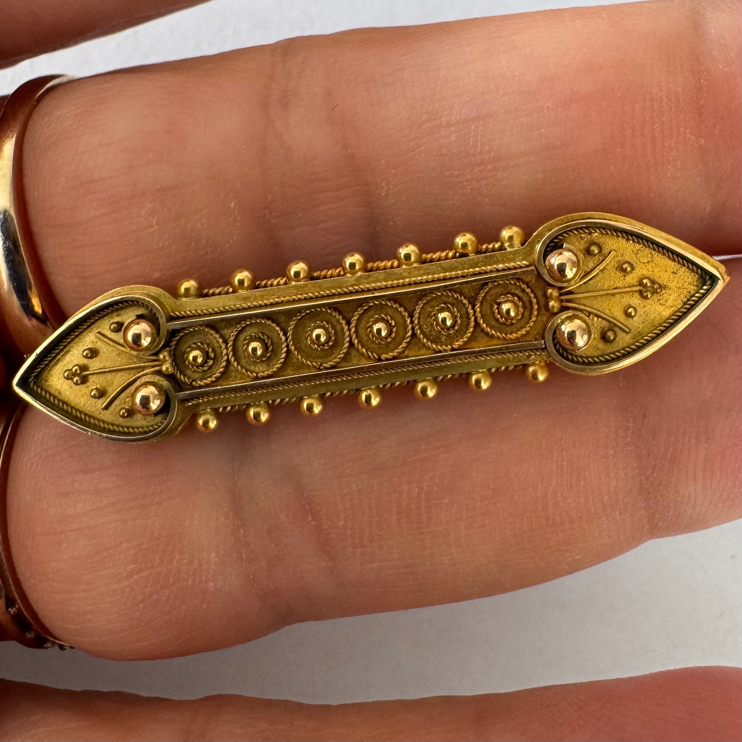 14K gold brooch featuring an ornate geometric design with intricate gold detailing & symmetrical decorative motifs.