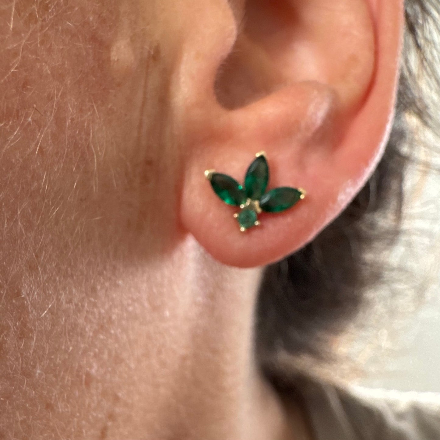 עגילים צמודיפ לאוזן מזהב 14 קראט, בעיצוב פרח עדין משובצים אבני אמרלד בחיתוך מרקיזה היוצר מראה אלגנטי, נקי ועל-זמני.