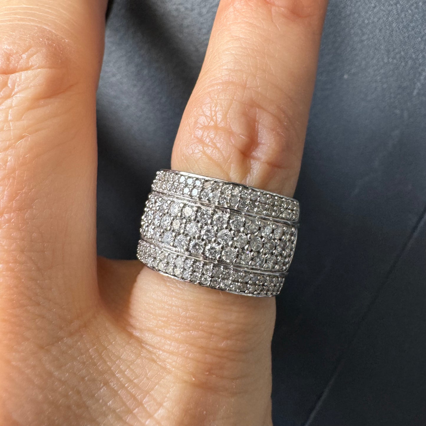 טבעת זהב לבן 18 קראט בעיצוב רחב ומרשים, משובצת יהלומים בשיבוץ פאווה צפוף המעניק ברק עשיר ונוכחות יוקרתית מכל זווית.
