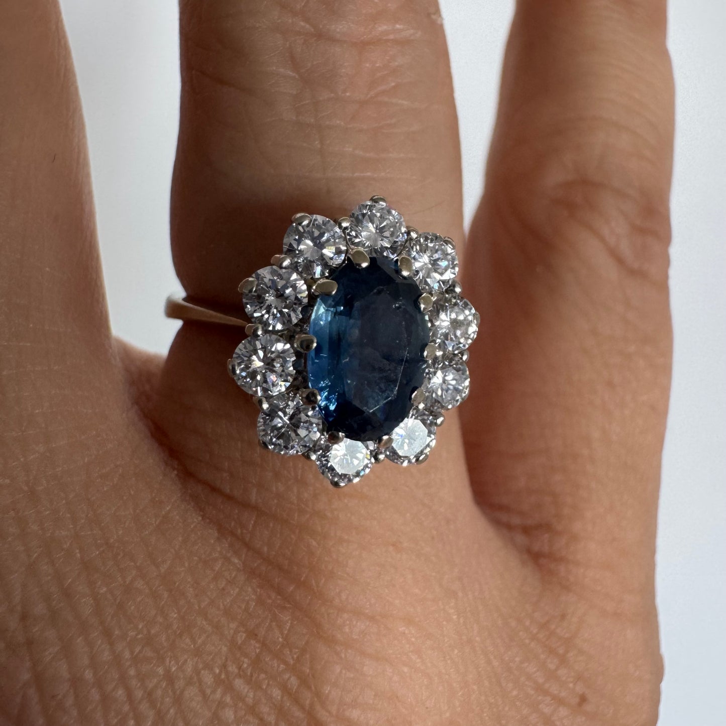 18K gold ring featuring a deep blue Sapphire at its center, surrounded by a sparkling halo of Diamonds