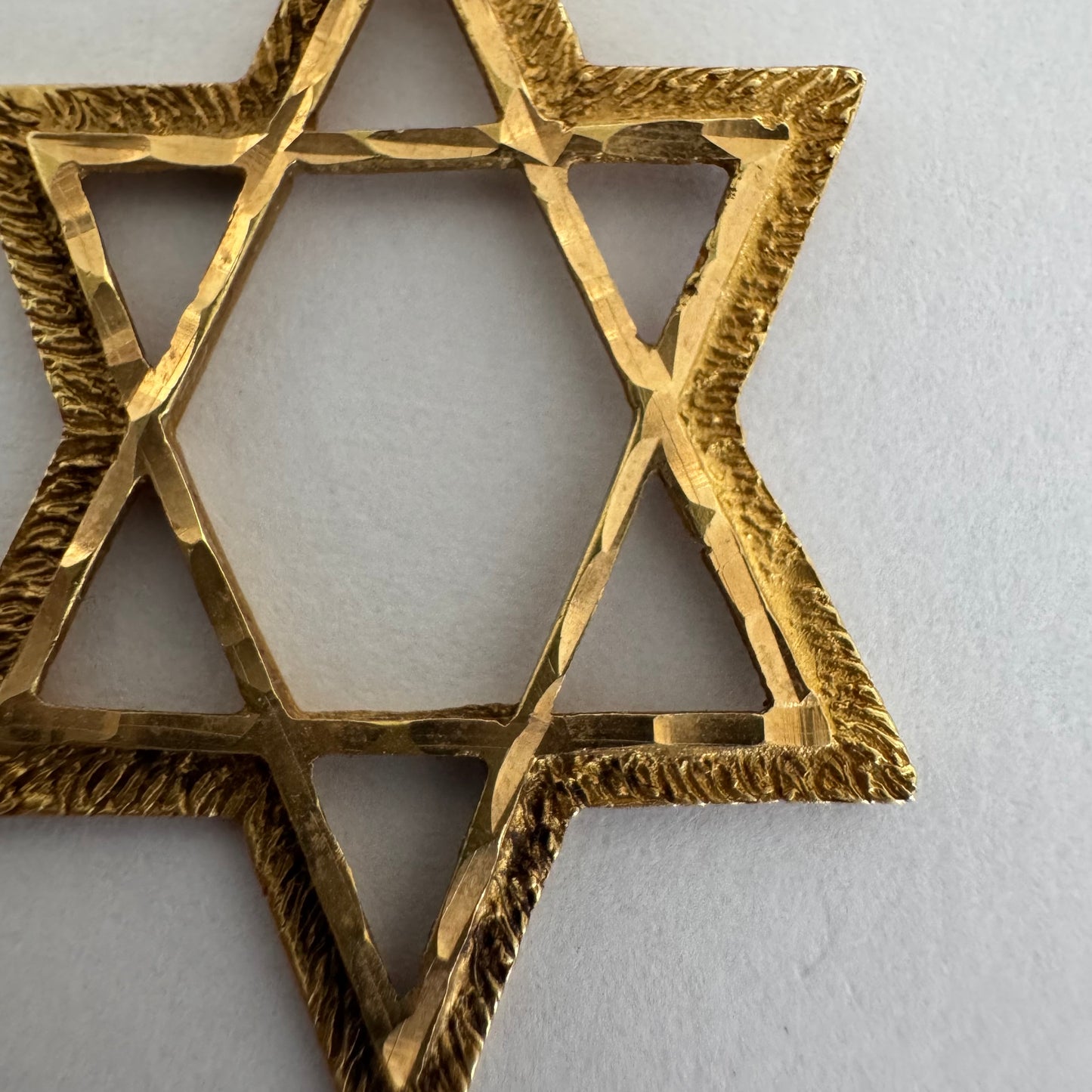 14K gold Star of David pendant with textured detailing and an open design.