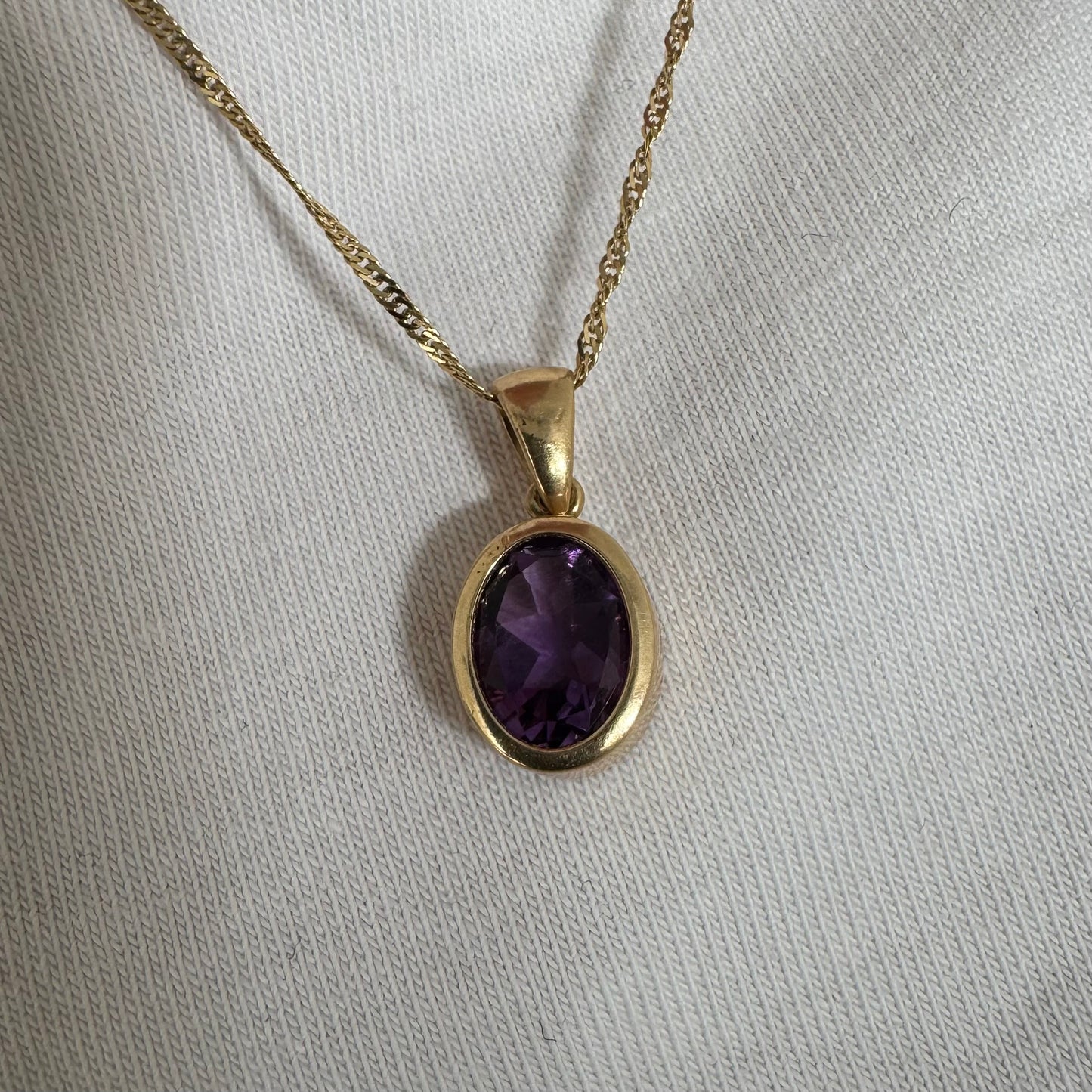 14K yellow gold necklace set with an oval-cut Amethyst in a smooth, classic bezel setting.