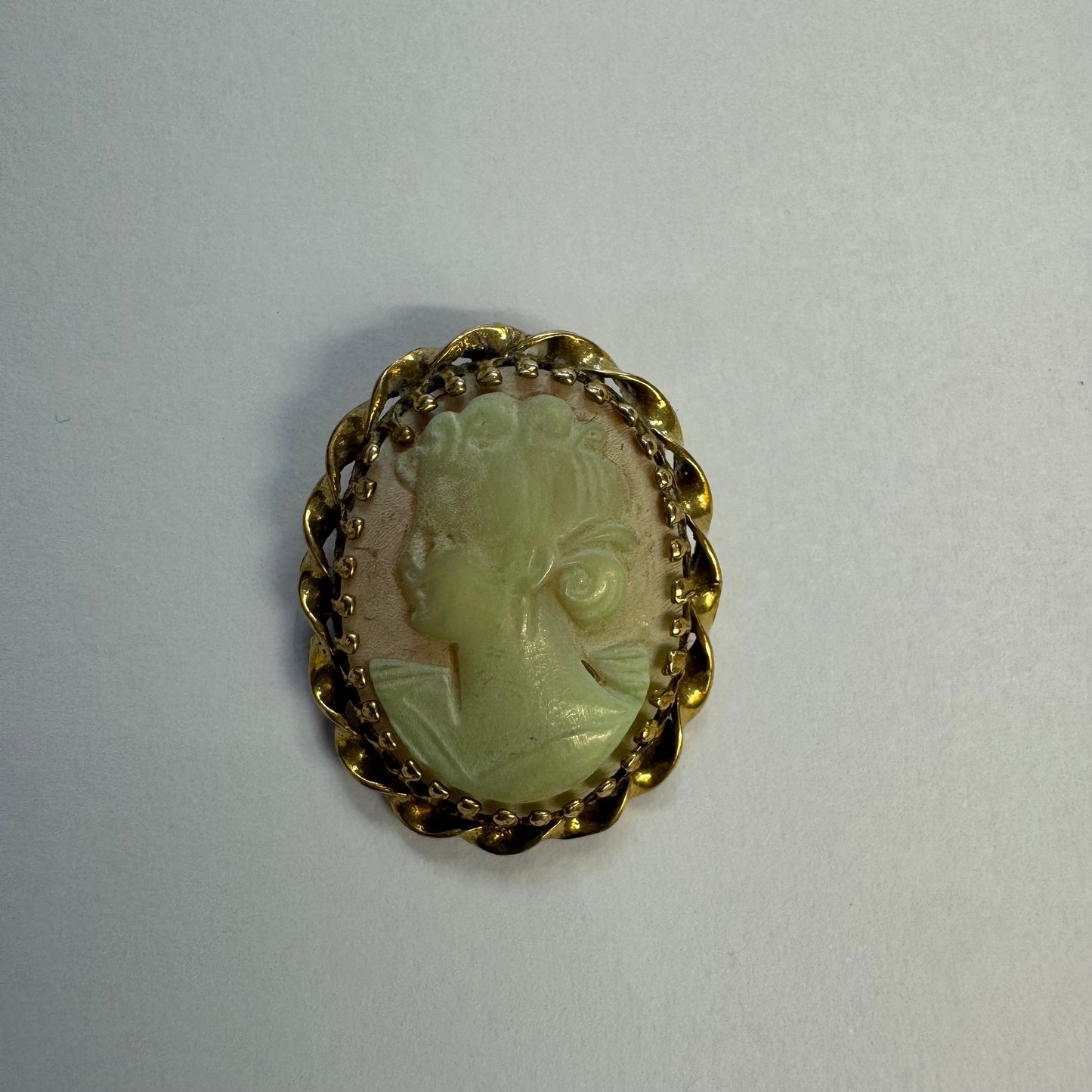 14K gold vintage cameo brooch featuring a hand-carved figure in a soft green tone, set in a classic decorative gold frame.