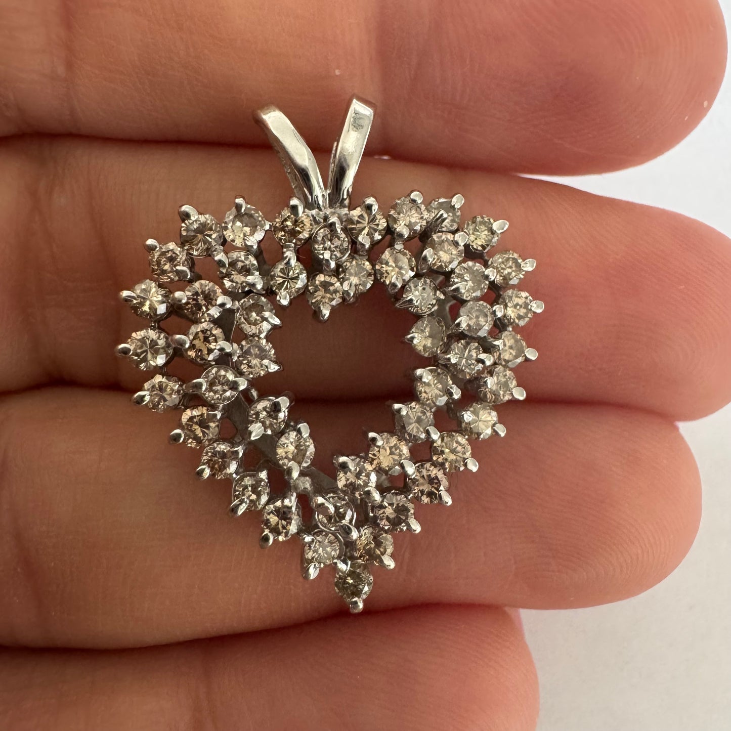 תליון לב זהב לבן 14 קראט, משובץ יהלומים בשיבוץ שיניים עדין היוצר מראה עשיר ומלא ברק.