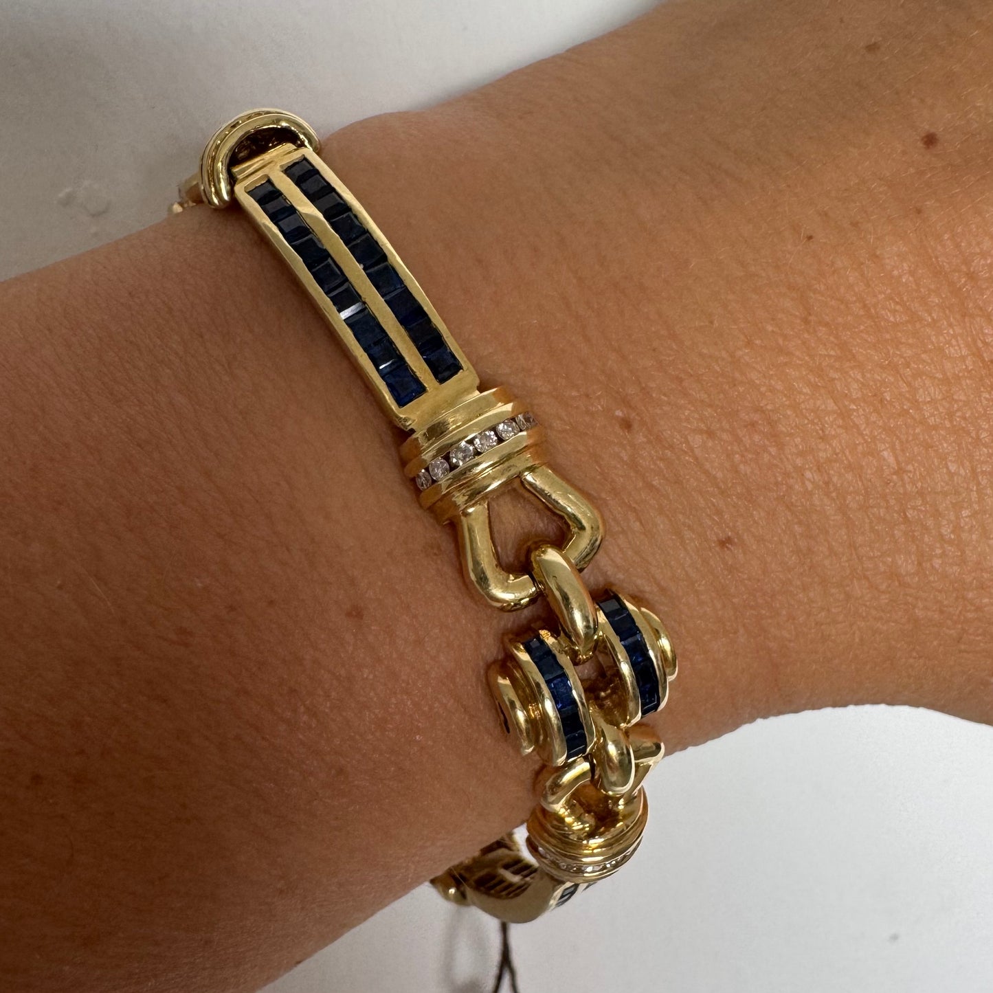 18K gold bracelet featuring a bold link design set with deep blue Sapphires and a subtle Diamond accent at the center.
