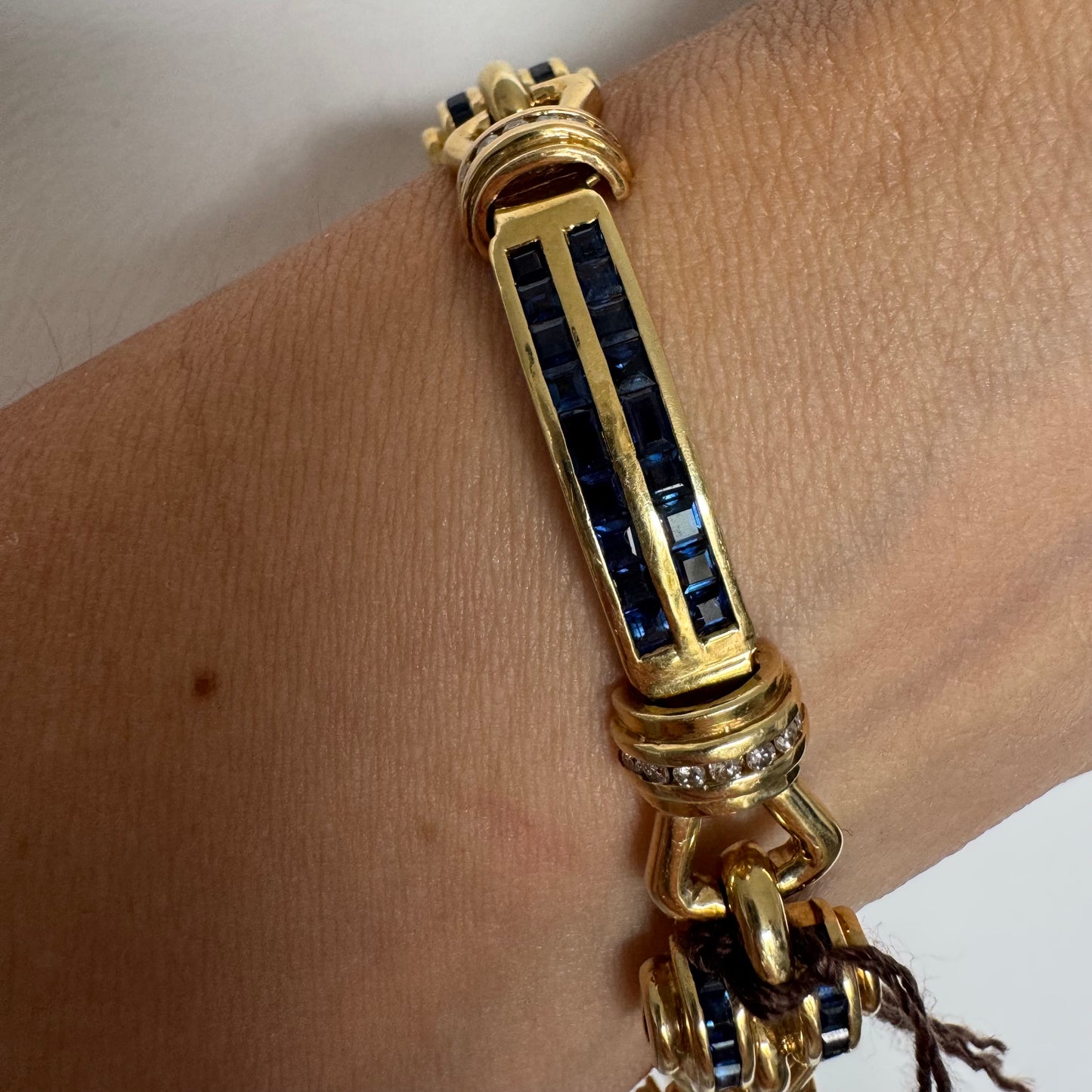 18K gold bracelet featuring a bold link design set with deep blue Sapphires and a subtle Diamond accent at the center.