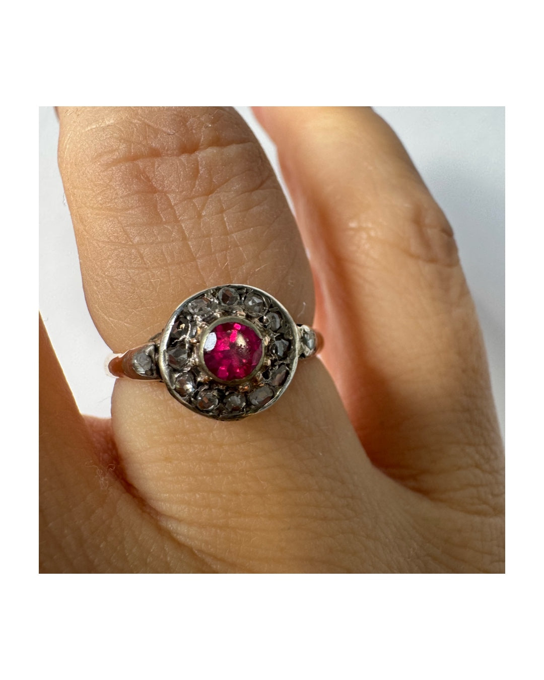 18K gold ring set with a round Ruby at the center, surrounded by a halo of old-cut Diamonds.