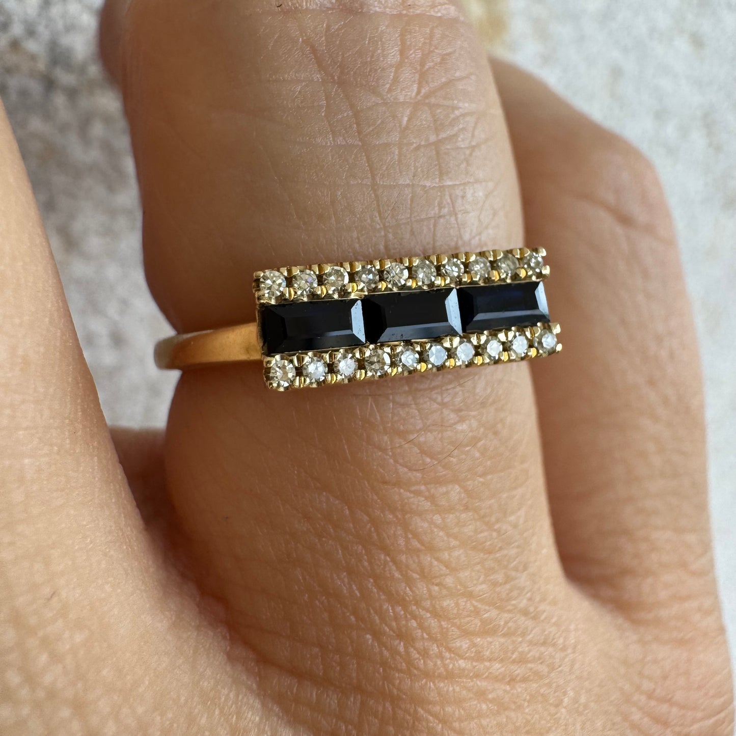 14K gold ring set with baguette-cut Sapphire framed by sparkling Diamonds