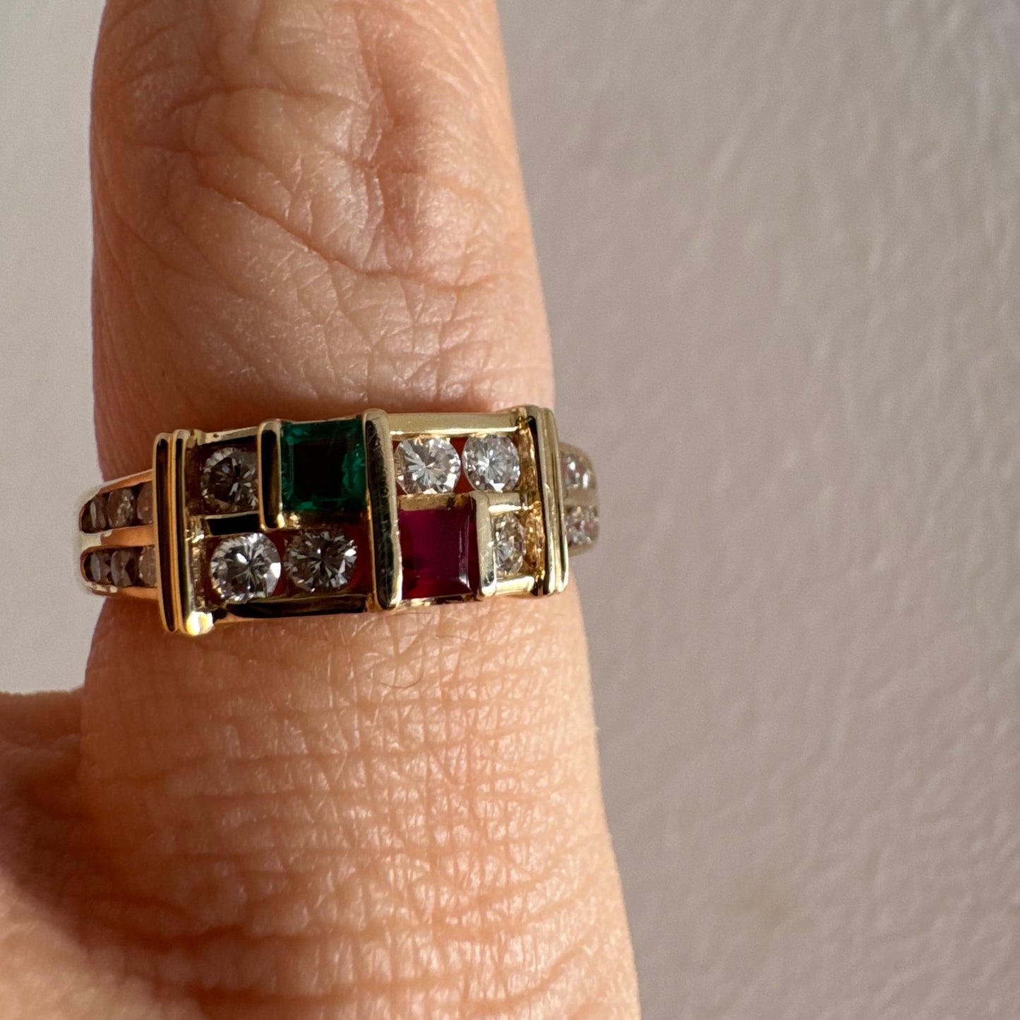 טבעת זהב צהוב 18 קראט בעיצוב גאומטרי מדורג, משובצת יהלומים עגולים לצד אבני אמרלד ורובי בחיתוך מלבני.