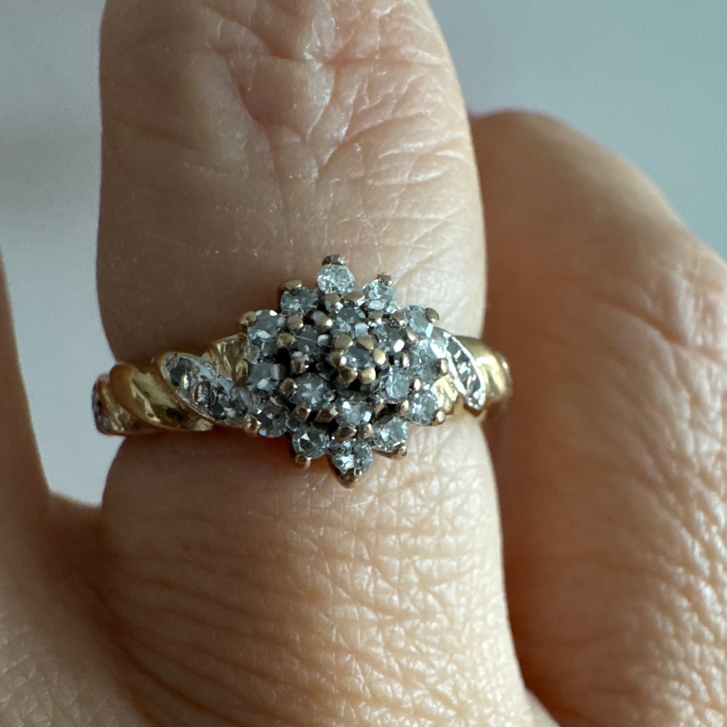 טבעת זהב צהוב 9 קראט משובצת יהלומים בעיצוב פרח עדין.