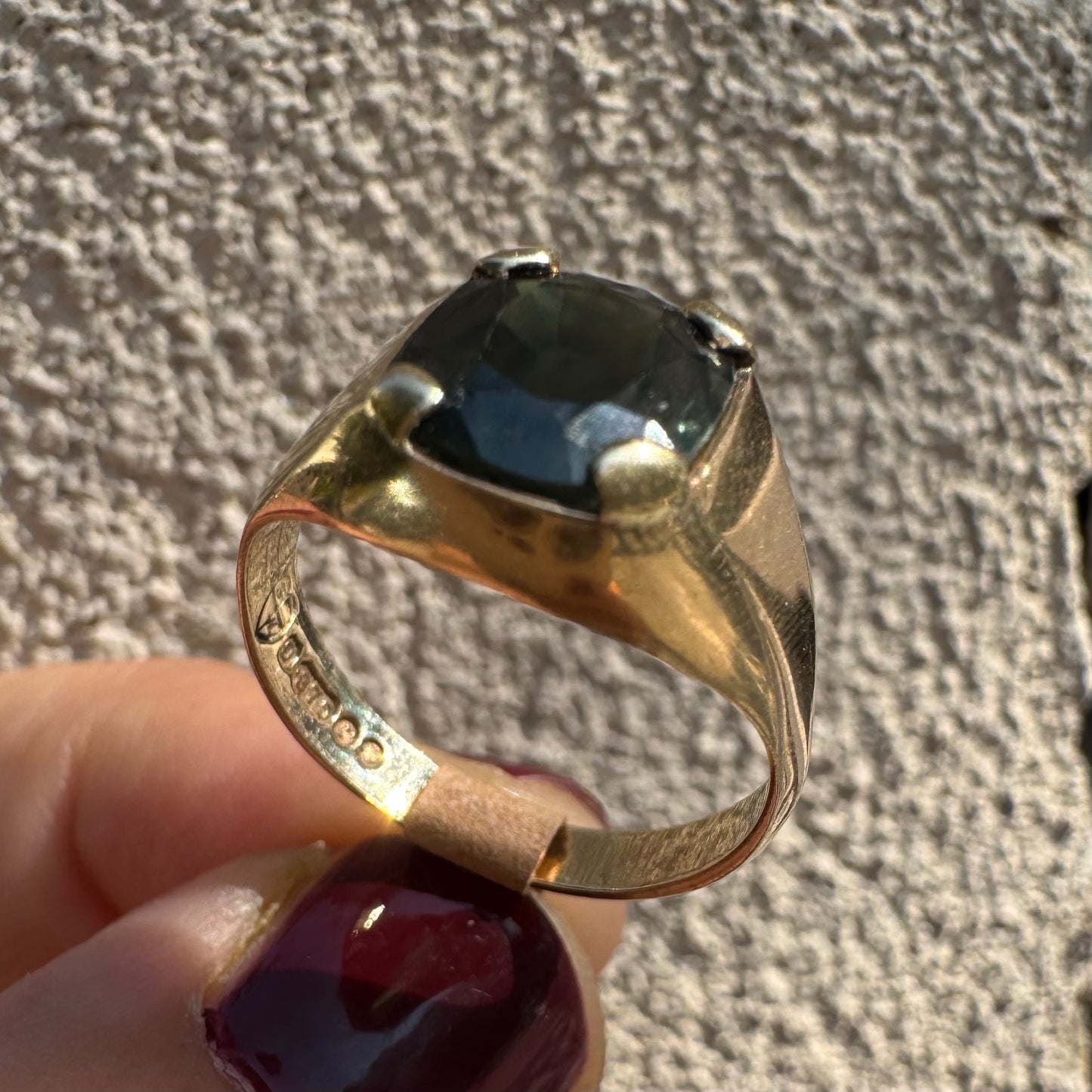 טבעת זהב 9 קראט משובצת ספיר ירוק כהה בחיתוך כרית ובתפסים עבים, בעיצוב נקי ובעל נוכחות. 