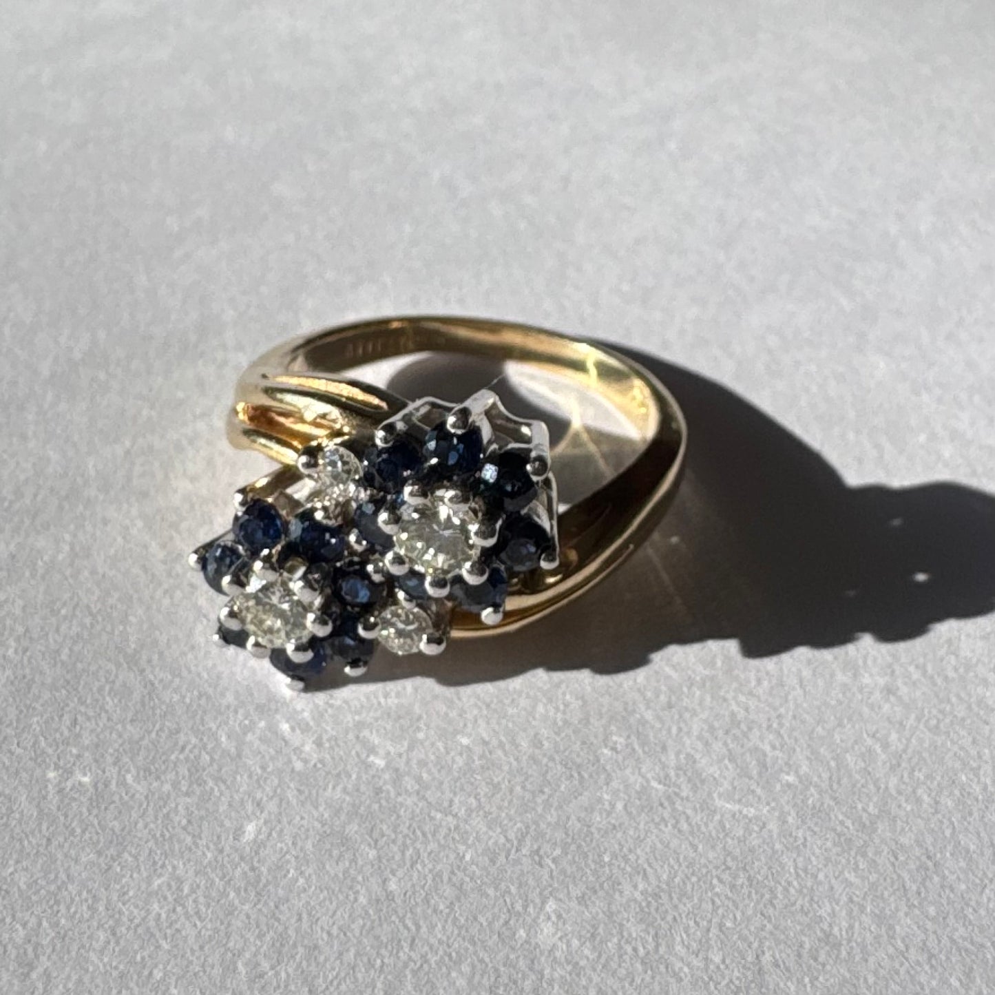 טבעת זהב צהוב 14 קראט משובצת אבני ספיר ויהלומים בעיצוב פרחים כפול.