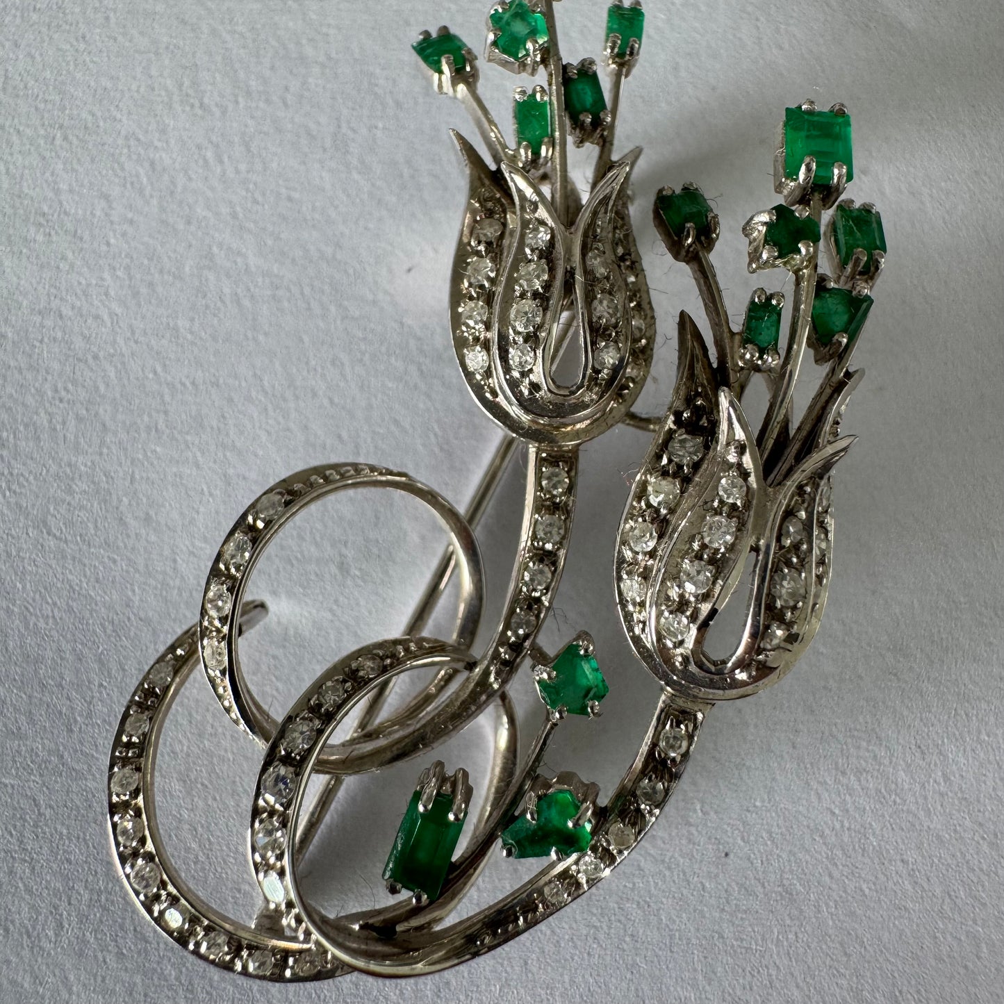 18K gold vintage brooch featuring an elegant floral design set with vibrant Emeralds and sparkling Diamonds.