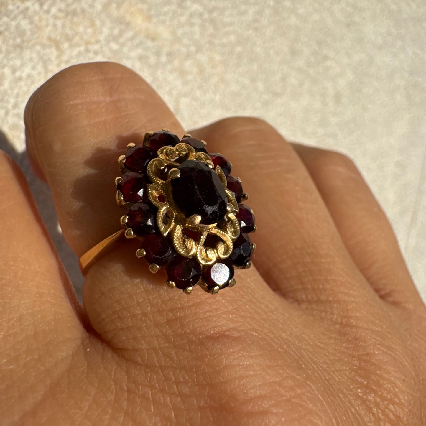 18K gold ring adorned with deep red Garnet gemstones, arranged in a radiant oval composition