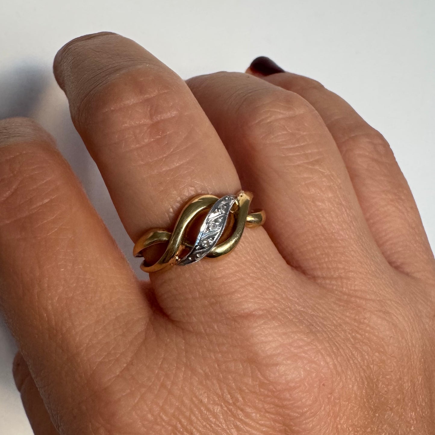 טבעת זהב צהוב 18 קראט בעיצוב קשר קלאסי, בשילוב אלמנט מרכזי מזהב לבן משובץ יהלומים עדינים.