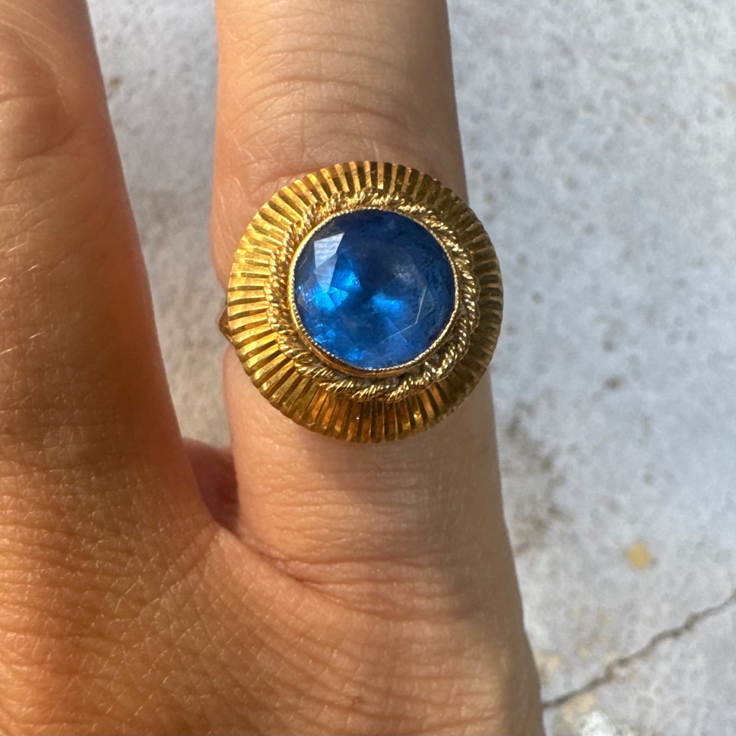 18K gold ring featuring a vibrant round Blue Topaz set in a textured gold bezel.
